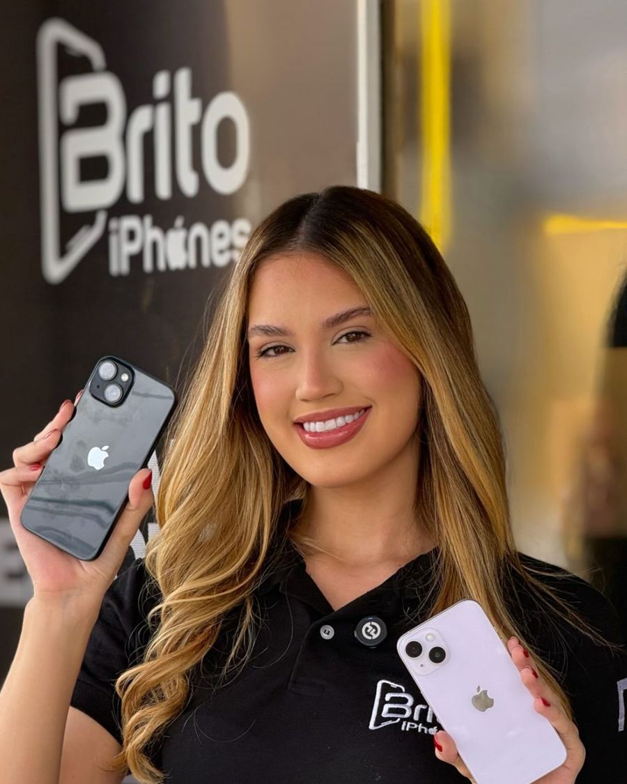 Atendente da Brito iPhones mostra dois iPhones em frente à loja